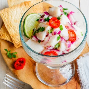 ceviche peruano de corvina casero servido en copa de vidrio con ají rojo y cebolla morada