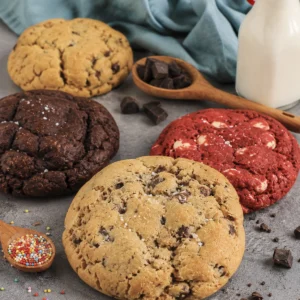 Crumbl Cookies caseras 6 Crumbl cookies caseras recién horneadas con chocolate, red velvet y chips, servidas con leche sobre una mesa gris.