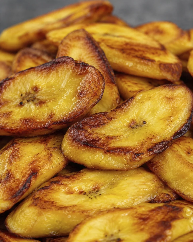 Plátanos maduros fritos 5 Plátanos maduros fritos en tajadas y mitades, acompañados con queso fresco sobre una tabla de madera.