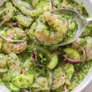 Cuchara con camarón en salsa verde de cilantro, pepino y cebolla morada para una receta de aguachile fresco.
